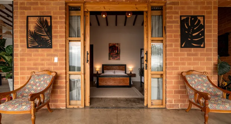 Entrada de la habitación familiar con puertas de madera y sillas — Finca Hotel Los Balcones, Filandia